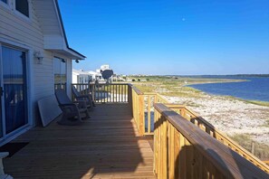 A wooden deck with chairs, a satellite dish, and a view of the beach and ocean. - Dog friendly home with private beach, internet and washer and dryer (Gulf Shores)