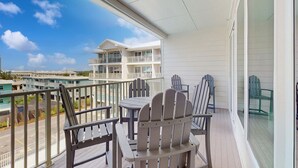 Een balkon met Adirondack-stoelen, een tafel en uitzicht op andere gebouwen.