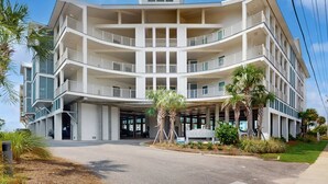 Een hotel met meerdere verdiepingen, balkons, een overdekte ingang en palmbomen.