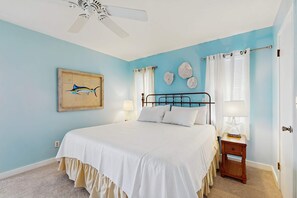 A bedroom with a bed, a ceiling fan, a nightstand, and a wall with a framed picture. - Dog-friendly beachfront home w Gulf views, spacious deck, WiFi, AC, W&D (Gulf Shores)