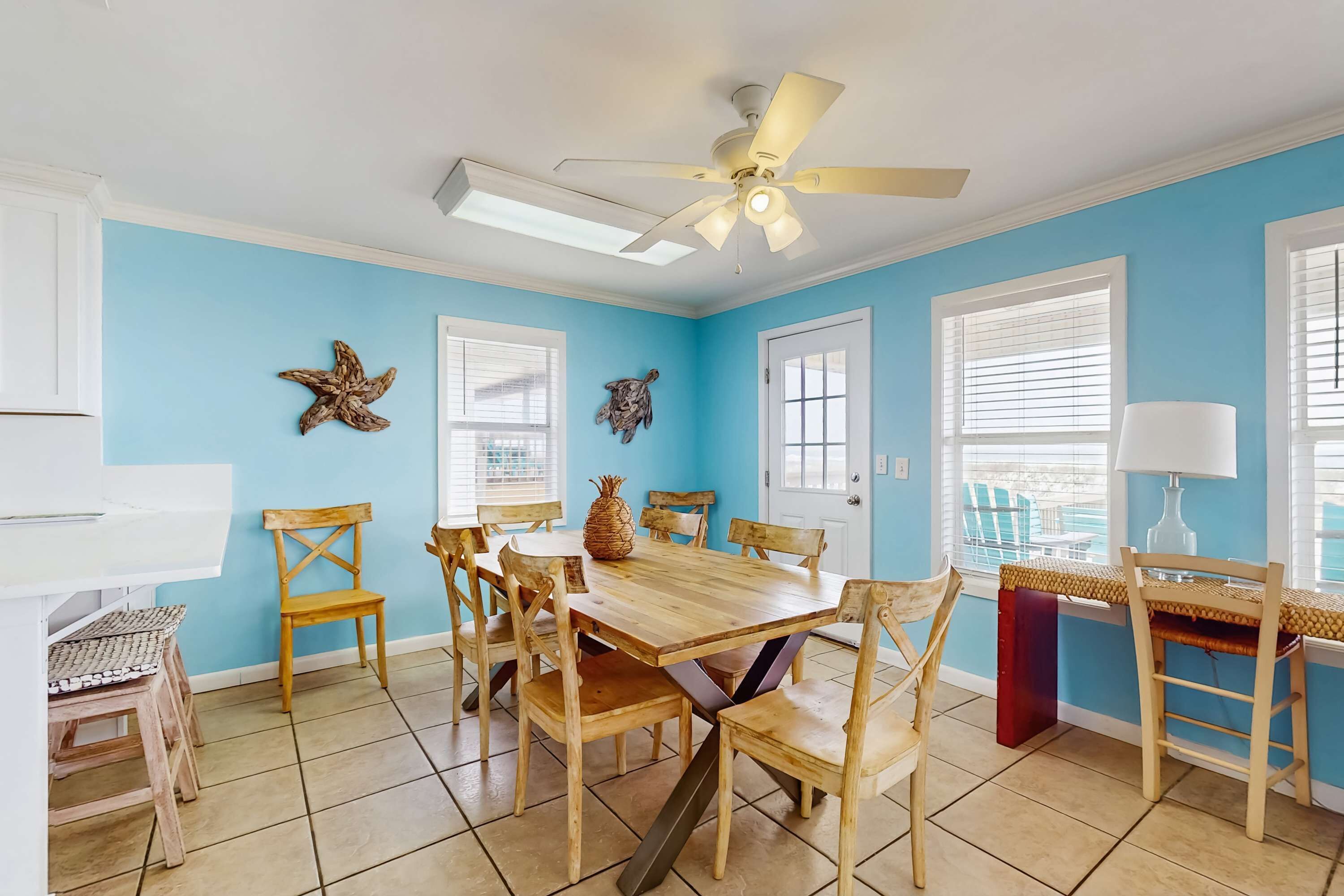 A dining area with a wooden table and chairs, a ceiling fan, and decorative wall art.