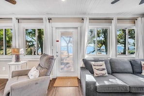A modern living room with a sofa, a chair, and a lamp. - Charming bay front home with WiFi, central AC, balcony, & deck (Orange Beach)