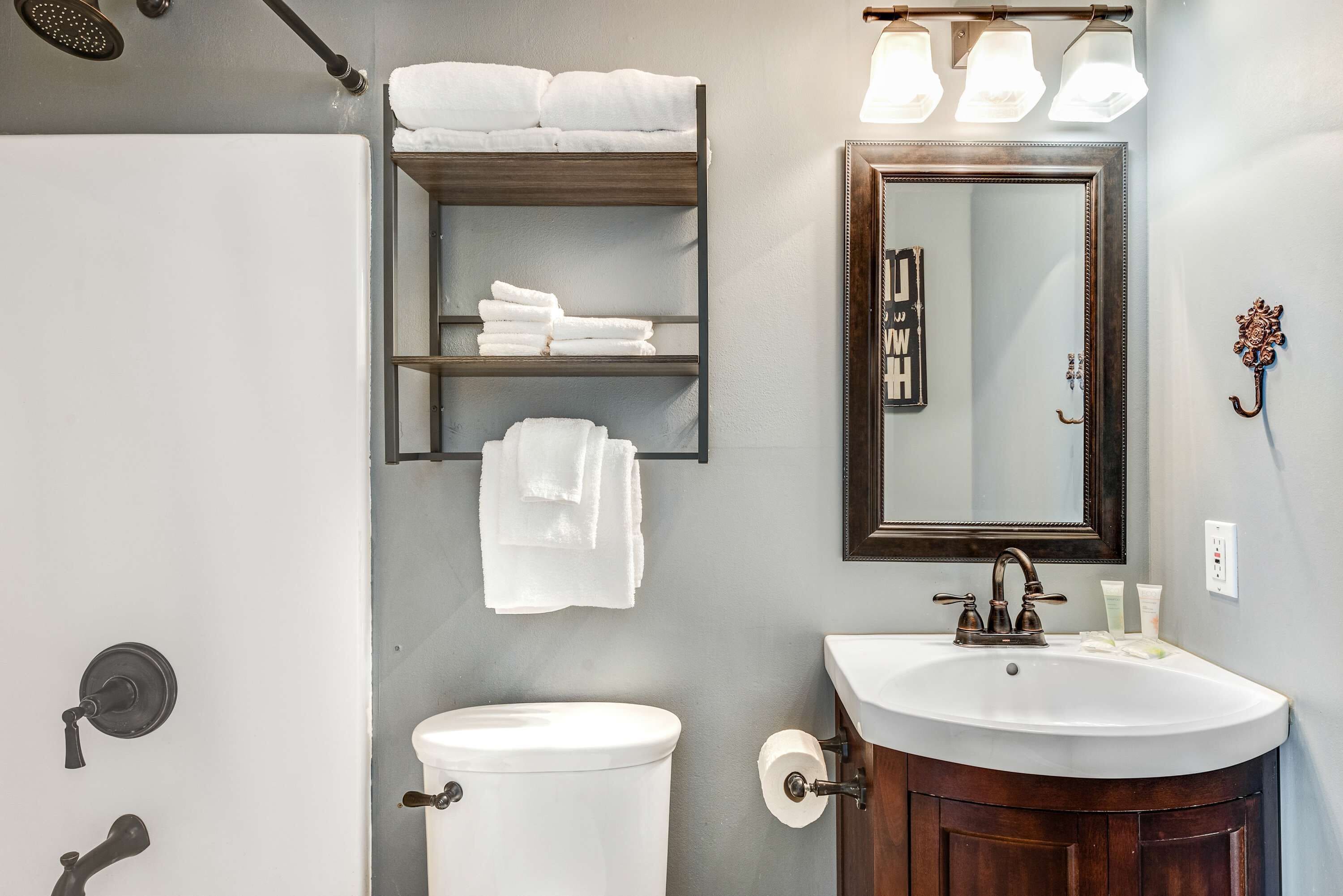 A bathroom with a toilet, sink, towel rack, and mirror.