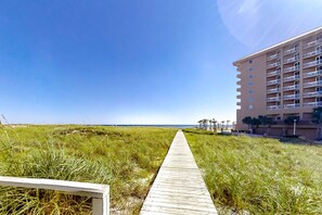 A pathway leading to a beachfront hotel with a clear sky. - Convenient and Comfortable Suite in Beachfront Resort w/Shared Pool, Free WiFi (Orange Beach)