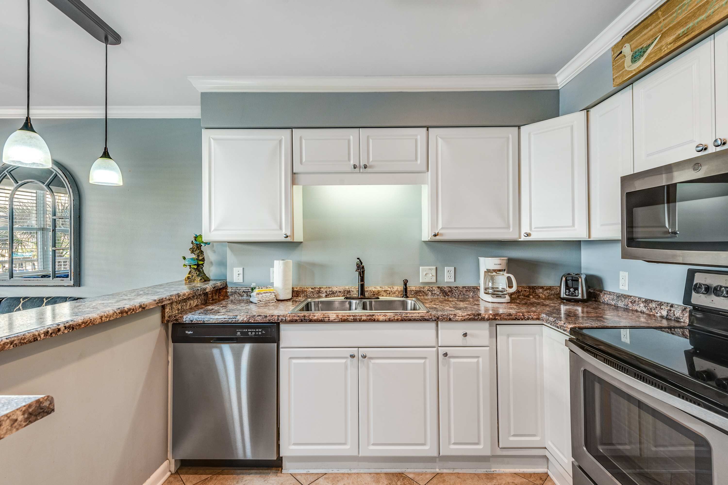 A kitchen with white cabinets, a stainless steel dishwasher, a double oven, and a granite countertop.
