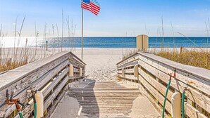 A wooden boardwalk leading to a beach with an American flag, sandy beach, and ocean view. - Wonderful Condo in Beachfront Complex w/Shared Pool & Hot Tub, Free WiFi, AC (Orange Beach)