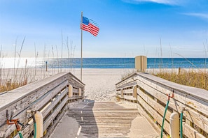 A wooden boardwalk leading to a beach with an American flag, sandy beach, and ocean view. - Wonderful Condo in Beachfront Complex w/Shared Pool & Hot Tub, Free WiFi, AC (Orange Beach)