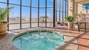 A hot tub with a view of a building and palm trees through large windows. - Wonderful Condo in Beachfront Complex w/Shared Pool & Hot Tub, Free WiFi, AC (Orange Beach)