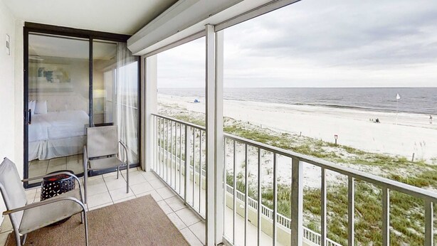 A balcony with a view of the beach, a bed, and a chair. - Wonderful Condo in Beachfront Complex w/Shared Pool & Hot Tub, Free WiFi, AC (Orange Beach)