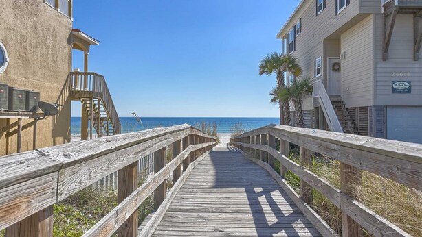 A wooden boardwalk leading to a beach, flanked by buildings with balconies and a clear view of the ocean. - Beachfront Suite with Free WiFi, Elevator, Shared Pool, and Central AC (Orange Beach)