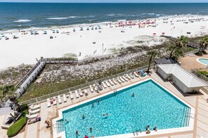 Ein Poolbereich mit Blick auf den Strand, Liegestühle und eine Terrasse mit Meerblick.
