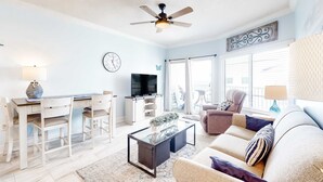Un salon équipé d’un ventilateur de plafond, d’un téléviseur, d’un canapé, d’une table basse et d’un coin repas avec des chaises et une table.