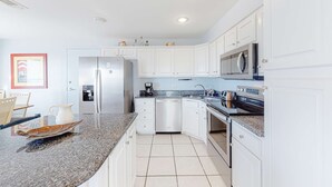 Una cocina moderna con armarios blancos, electrodomésticos de acero inoxidable y encimera de granito.