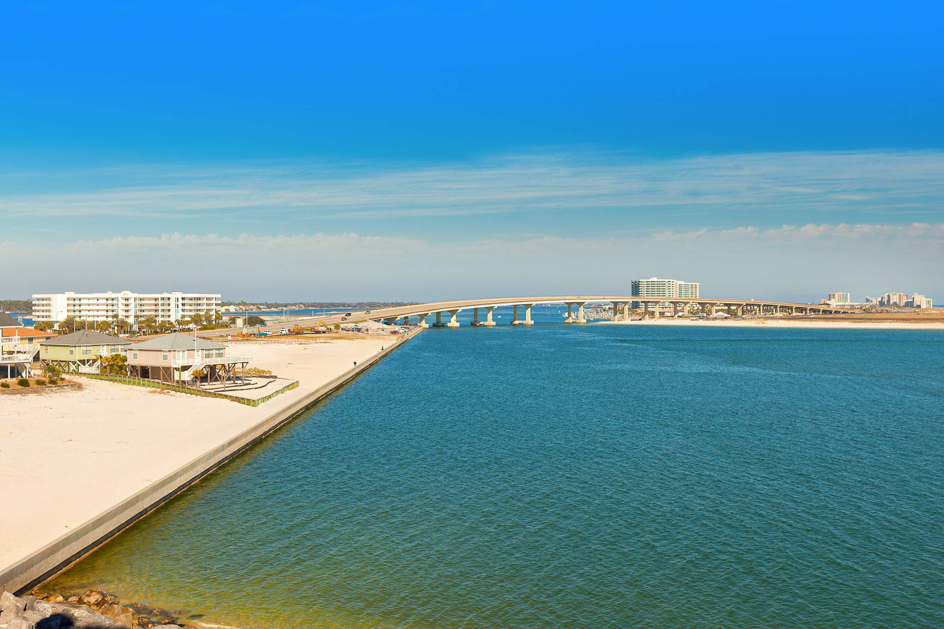 Un ponte costiero con una spiaggia e degli edifici sullo sfondo.