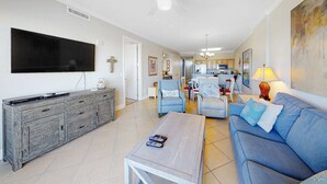 Una sala de estar con sofá, mesa de centro, televisor y comedor con sillas y mesa.