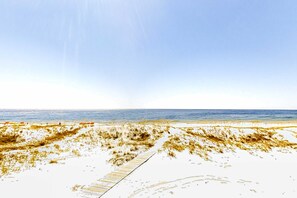 A beach with a wooden boardwalk leading to the water. - Gulf-front home on the beach with 3-tier deck, Gulf views & pool access (Orange Beach)