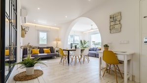 Un salon moderne comprenant un canapé, une table à manger et des chaises, un coin cuisine et une grande porte en arc de cercle.