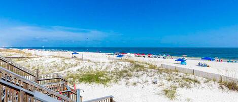 A beach with wooden boardwalks, sandy dunes, and beach umbrellas.