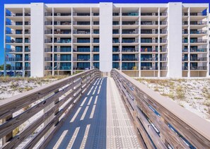Un hotel de varios pisos con un atrio central, balcones y un paseo marítimo de madera que conduce a la entrada.