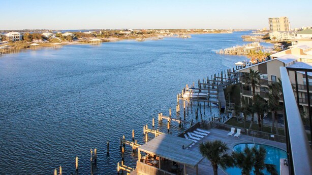 A waterfront hotel with a pool, dock, and views of the water. - Coastal escape with 2 water-view balconies, 2 pools, tennis & beach access (Orange Beach)