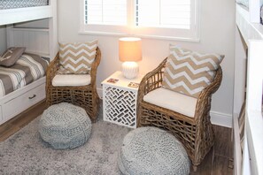 A cozy room with a bunk bed, two wicker chairs with cushions, a small table with a lamp, and a decorative basket. - Coastal escape with 2 water-view balconies, 2 pools, tennis & beach access (Orange Beach)