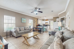 A spacious living room with a sofa, coffee table, and dining area. - Spacious condo with pool & screened porch (Orange Beach)