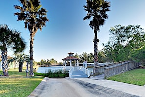 A gazebo with a red roof, a wooden bridge, and palm trees. - Spacious condo with pool & screened porch (Orange Beach)
