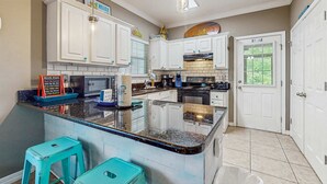 Una cocina con armarios blancos, encimera de granito, horno empotrado y ventana.
