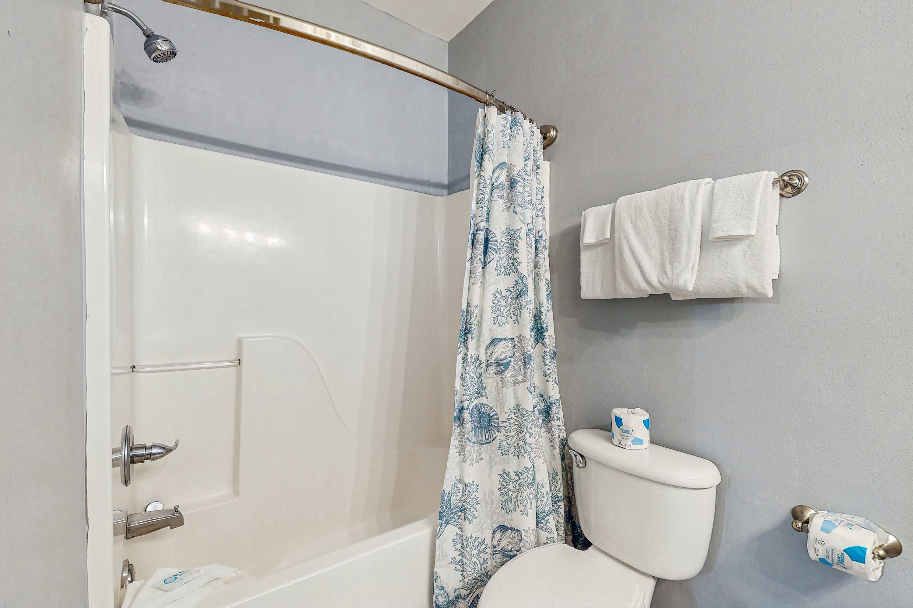 Une salle de bain avec douche, toilettes et porte-serviettes.