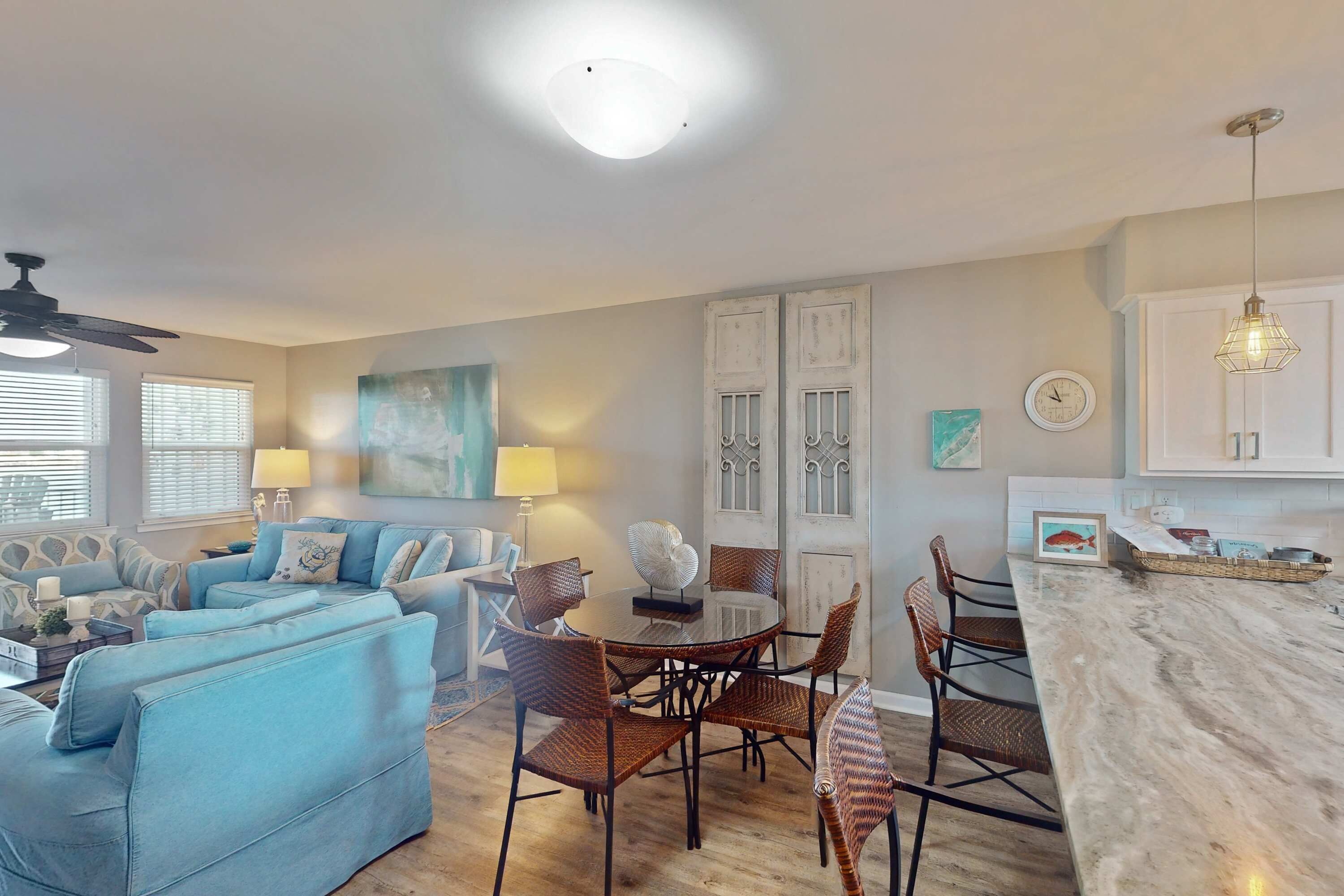 A living room with a sofa, dining table, chairs, and a kitchen area with cabinets and a countertop.