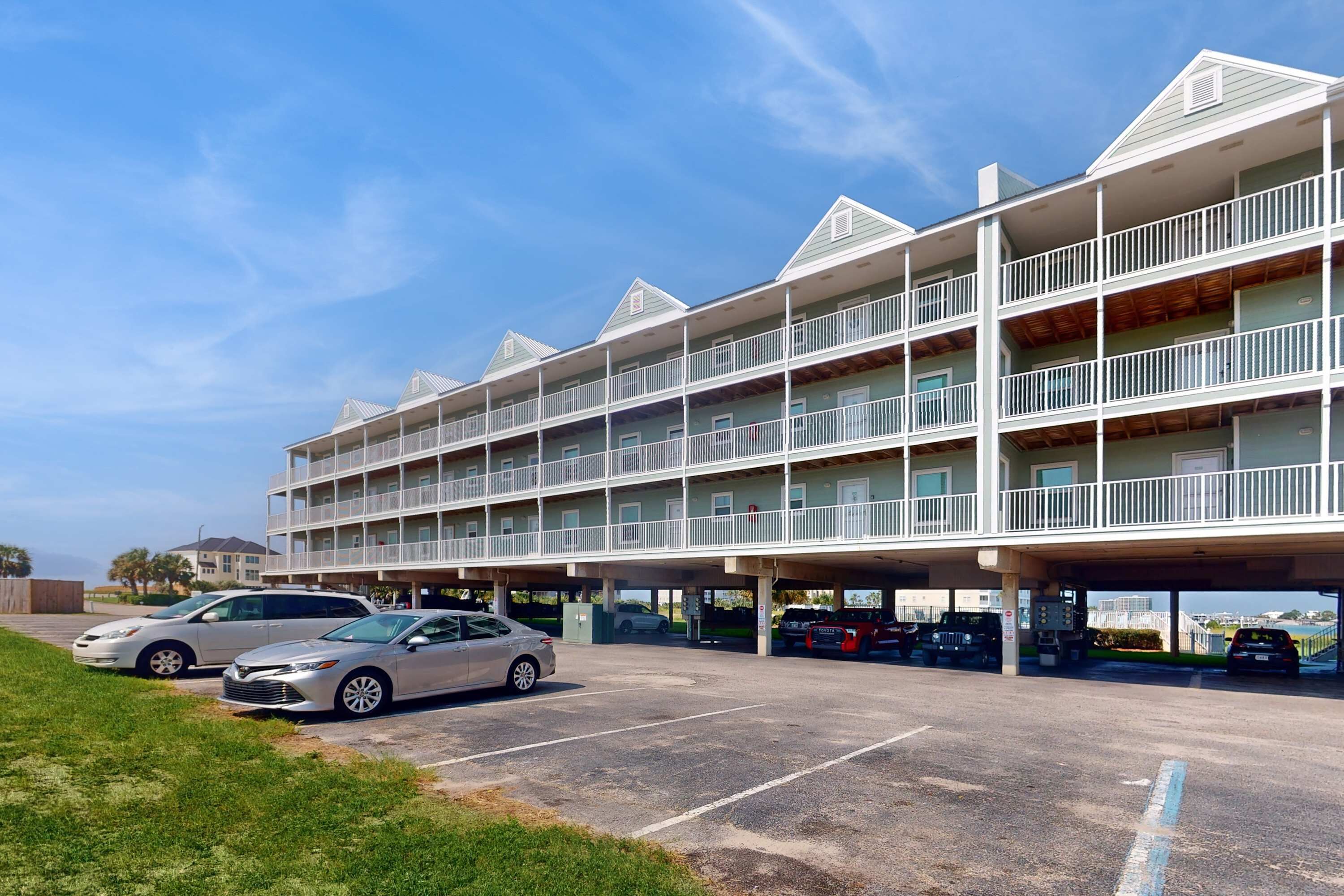 A multi-story hotel with a parking lot and several cars parked.