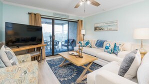 Ein Wohnzimmer mit Fernseher, Deckenventilator, Couchtisch und Sofa.