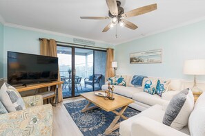 Ein Wohnzimmer mit Fernseher, Deckenventilator, Couchtisch und Sofa.