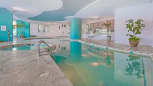 Una piscina interior con agua cristalina, suelo de baldosas y un diseño moderno del techo.