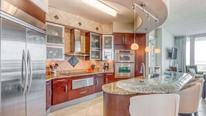 Una cocina moderna con electrodomésticos de acero inoxidable, encimera de granito y una isla central con taburetes de bar.