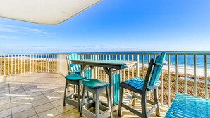 Eine Terrasse am Strand mit Tisch, Stühlen und Geländer, mit Blick auf das Meer.