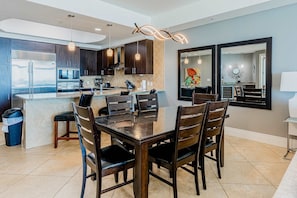 A modern kitchen with dark wood cabinets, stainless steel appliances, and a central island with seating. - Gulf-front condo with pool, tennis, lazy river & private hot tub (Orange Beach)