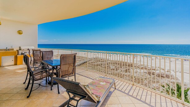 Ein Balkon mit Blick auf den Strand, Korbmöbel und Fliesenboden.