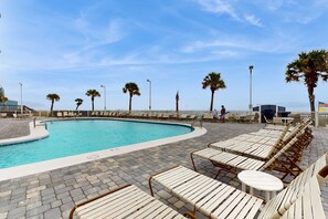 Ein Swimmingpool mit Liegestühlen und Palmen.
