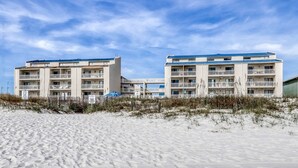 A beachfront hotel with multiple balconies and a sandy beach in the foreground.