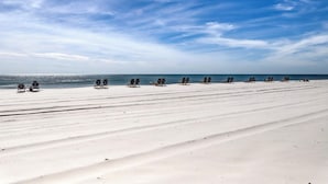 A beach with rows of sun loungers and a clear sky. - Gulf front condo with pools/hot tub - ocean view, covered balcony & washer/dryer (Orange Beach)