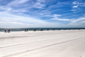 A beach with rows of sun loungers and a clear sky. - Gulf front condo with pools/hot tub - ocean view, covered balcony & washer/dryer (Orange Beach)
