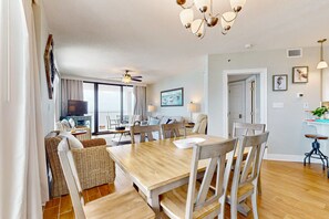 Ein Essbereich mit Holztisch und Stühlen, einem Fernseher im Hintergrund und einem Balkon mit Blick.