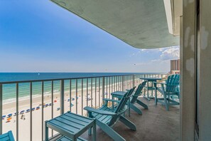 Ein Balkon mit Blick auf den Strand, Stühlen und Sonnenschirmen.