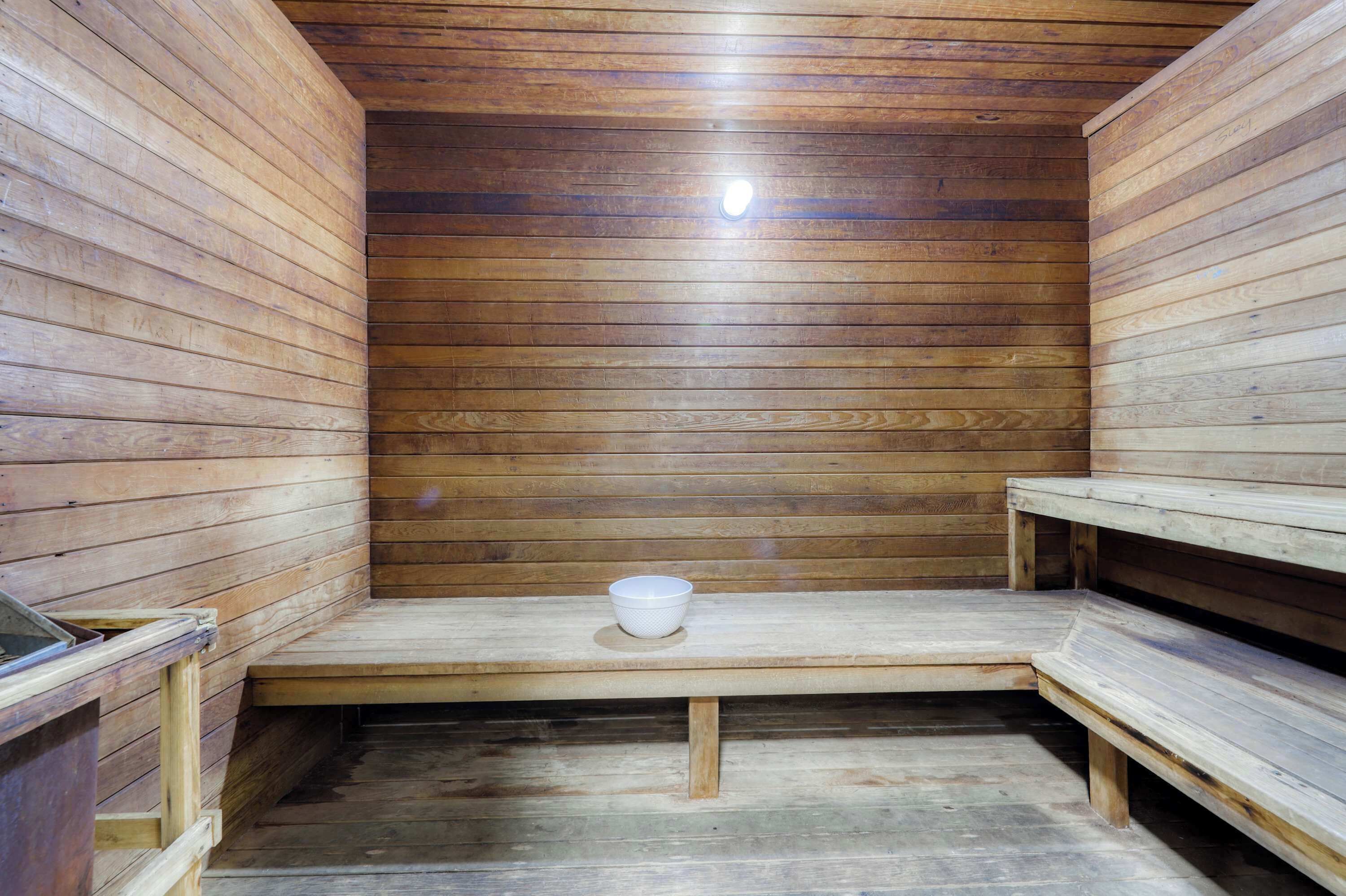 Uma sala de sauna com bancos de madeira e uma tigela branca.