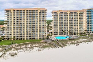 A high-rise hotel with multiple balconies, a swimming pool, and a beach area. - Gulf front condo w/ a private, furnished balcony, shared pools, hot tub, gym (Orange Beach)