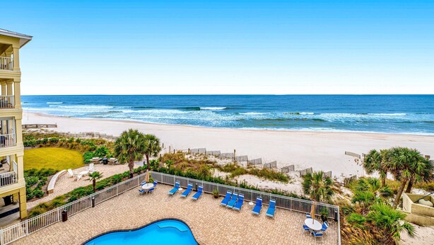 A pool area with lounge chairs and a view of the ocean. - Beachfront condo with Gulf front shared pool, private balcony, and grilling area (Orange Beach)
