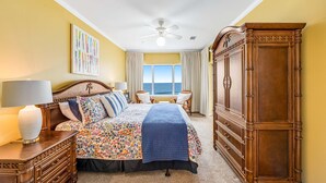 A bedroom with a bed, nightstands, a dresser, a ceiling fan, and a window with curtains. - Beachfront condo with Gulf front shared pool, private balcony, and grilling area (Orange Beach)