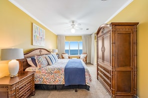 A bedroom with a bed, nightstands, a dresser, a ceiling fan, and a window with curtains. - Beachfront condo with Gulf front shared pool, private balcony, and grilling area (Orange Beach)