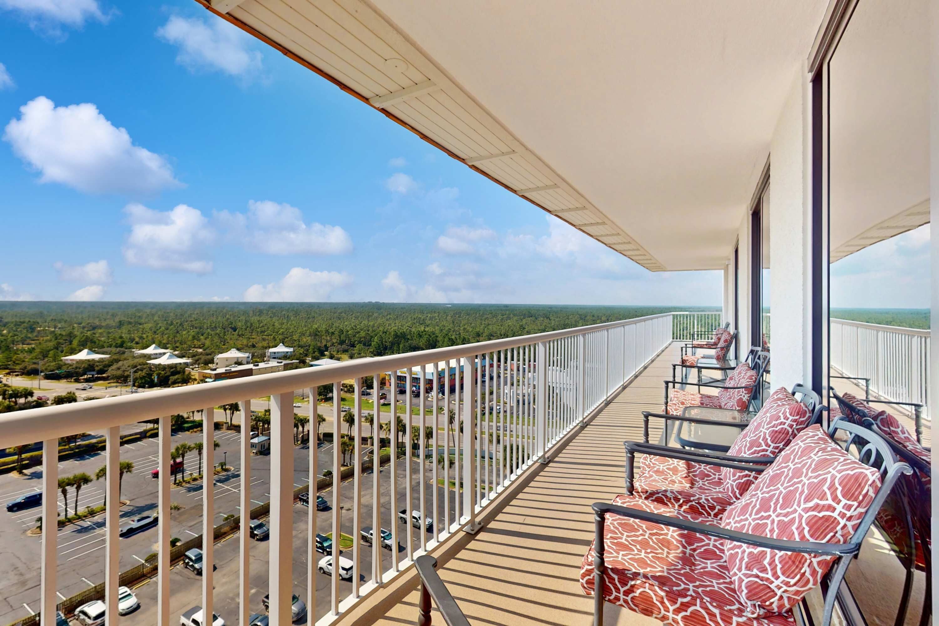 A balcony with a view of a parking lot and greenery.